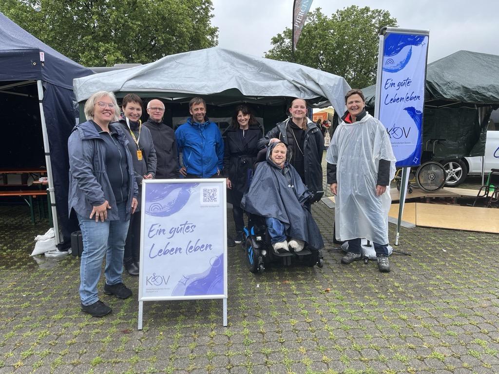 M&auml;nner und Frauen stehen im Halbkreis vor Pavillon
