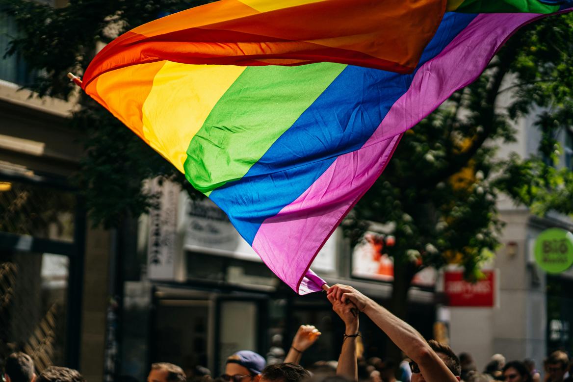 Mensch h&auml;lt Fahne in Regenbogenfarben hoch