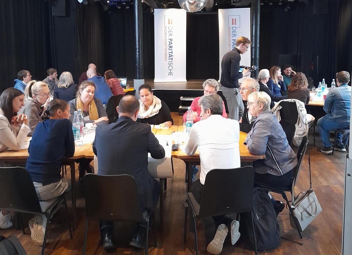 Drei Thementische mit diskutierenden Menschen